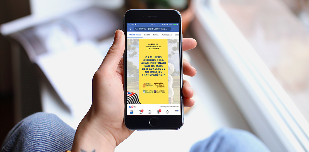 Na imagem está uma mão segurando um smartphone. Na tela do celular está aberto um post no Facebook com o texto: “Os museus geridos pela ACAM Portinari são os mais bem avaliados no quesito transparência”. No final estão as logomarcas dos Museus Índia Vanuíre, Casa de Portinari e Felícia Leirner e  Auditório Claudio Santoro.