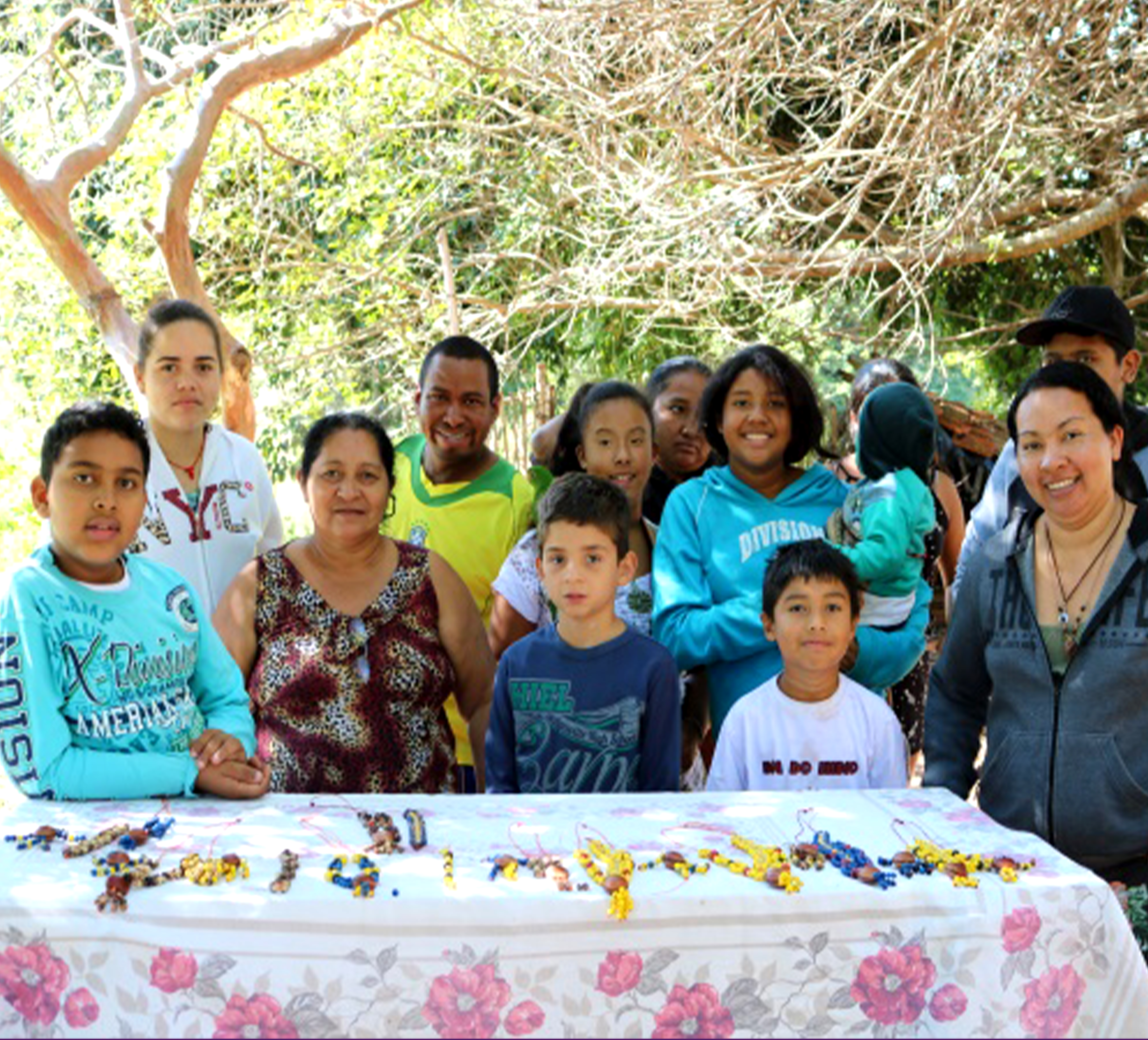 Nesta imagem, os participantes estão em pé, posando para a foto. Na frente deles está a mesa com as peças produzidas na oficina.
