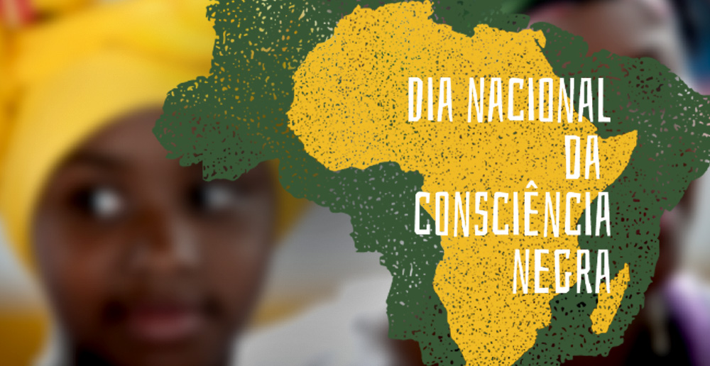 #PraCegoVer - Descrição da imagem para cegos: a arte mostra, em primeiro plano, um desenho do Brasil pintado em verde e amarelo. Por cima da peça aparece o texto “Dia Nacional da Consciência Negra”. Atrás, desfocado, está o rosto de uma jovem com turbante amarelo na cabeça.