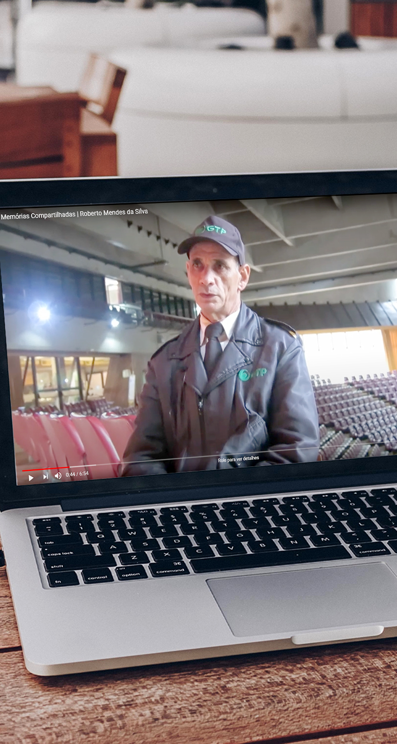 #PraCegoVer - Descrição da imagem para cegos: a imagem mostra um notebook aberto em cima de uma mesa de maneira. Na tela do computador aparece o vídeo do projeto, no qual mostra um homem sentado, uniformizado e com boné falando.