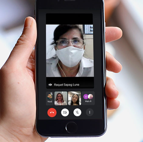 #PraCegoVer - Descrição da imagem para cegos: a arte mostra uma mão segurando um smartphone. Na tela aparece a foto de uma mulher participando de um bate-papo.