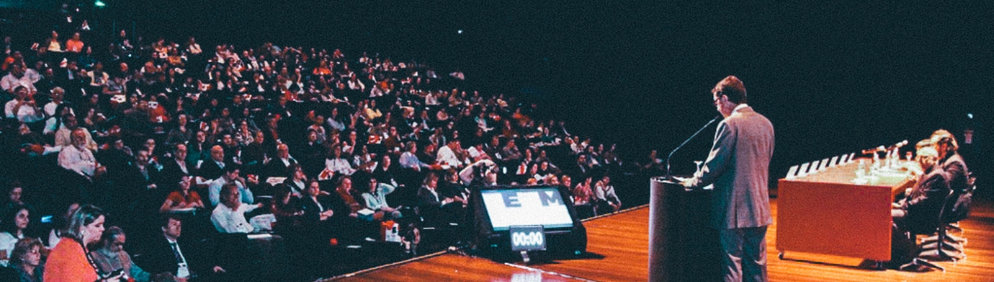 A imagem mostra pessoas assistindo uma apresentação