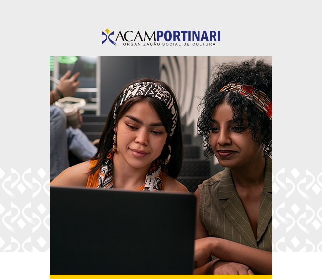 Na parte superior da imagem, sobre fundo cinza claro, aparece o logotipo da ACAM Portinari – Organização Social de Cultura. Ao centro, há uma fotografia em formato retangular. A imagem mostra duas mulheres sentadas lado a lado diante de um notebook. À esquerda, uma mulher de cabelos escuros e lisos usa uma faixa estampada na cabeça, brincos e uma blusa em tom alaranjado. À direita, outra mulher de cabelos cacheados presos parcialmente por uma faixa colorida veste uma blusa verde com listras discretas. Ambas observam a tela do computador à frente. Ao fundo, aparecem elementos desfocados de um ambiente interno e uma terceira pessoa parcialmente visível. Nas laterais da composição, sobre o fundo cinza, há padrões gráficos geométricos em tom branco. Na parte inferior da fotografia, uma faixa amarela destaca a base da imagem.
