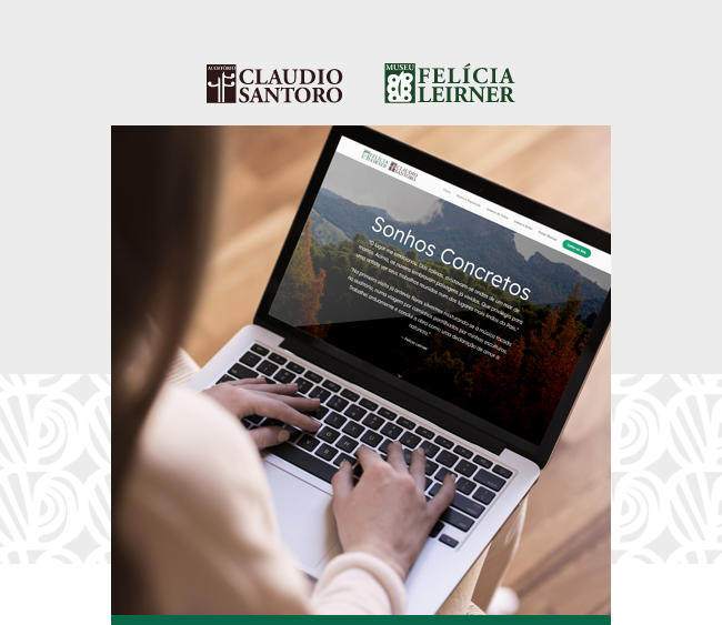 Na parte superior da imagem, sobre fundo cinza claro, aparecem os logotipos do Auditório Claudio Santoro e do Museu Felícia Leirner. Ao centro, uma fotografia em plano aproximado mostra uma pessoa utilizando um notebook apoiado no colo. O enquadramento destaca as mãos sobre o teclado e a tela do computador, onde aparece o site do museu com a frase “Sonhos Concretos” sobre uma imagem de paisagem montanhosa. A pessoa veste roupa clara e aparece desfocada em primeiro plano, com o foco voltado para o computador. O ambiente possui iluminação suave e piso de madeira ao fundo. Nas laterais inferiores da composição, elementos gráficos claros aparecem sobre a faixa cinza de fundo.