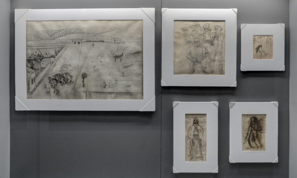 PraTodosVerem – A imagem mostra quatro quadros fixados em uma parede cinza. As obras são em preto e branco com molduras brancas e grossas.